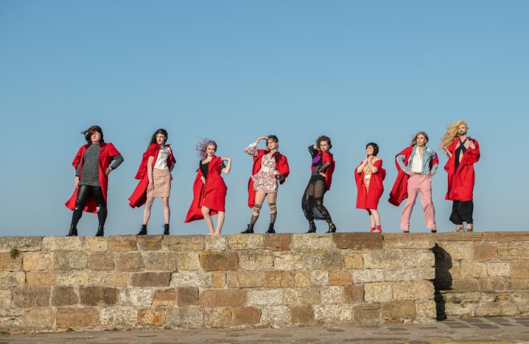 A group of students standing on St Andrews Pier wearing red gowns