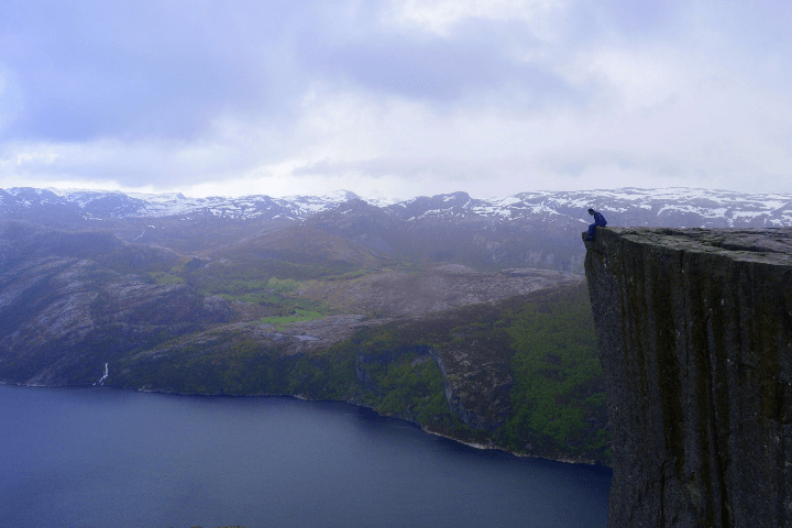 Photo of a student sitting on the edge of a cliff in Norway