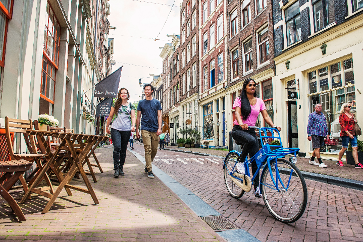 A cyclist and pedestrians on a street in Amsterdam