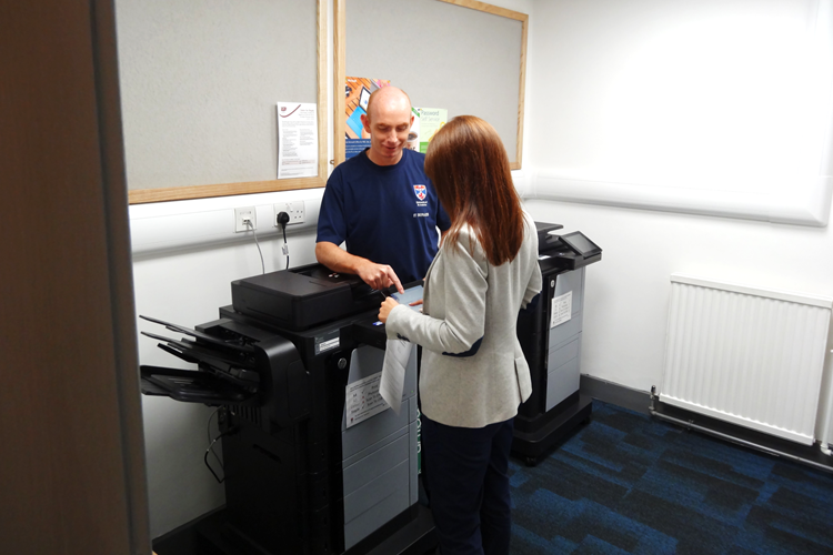 Staff member getting help beside printer