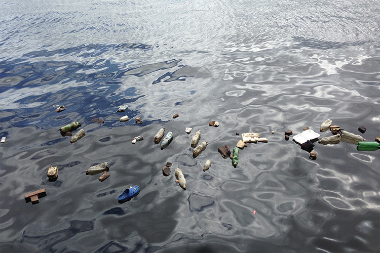 Plastic pollution on the surface of a black and blue sea