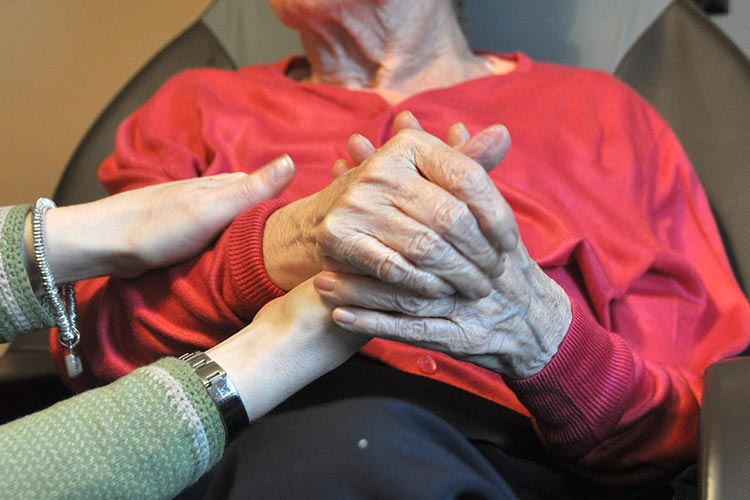 researcher holding hands with dementia patient